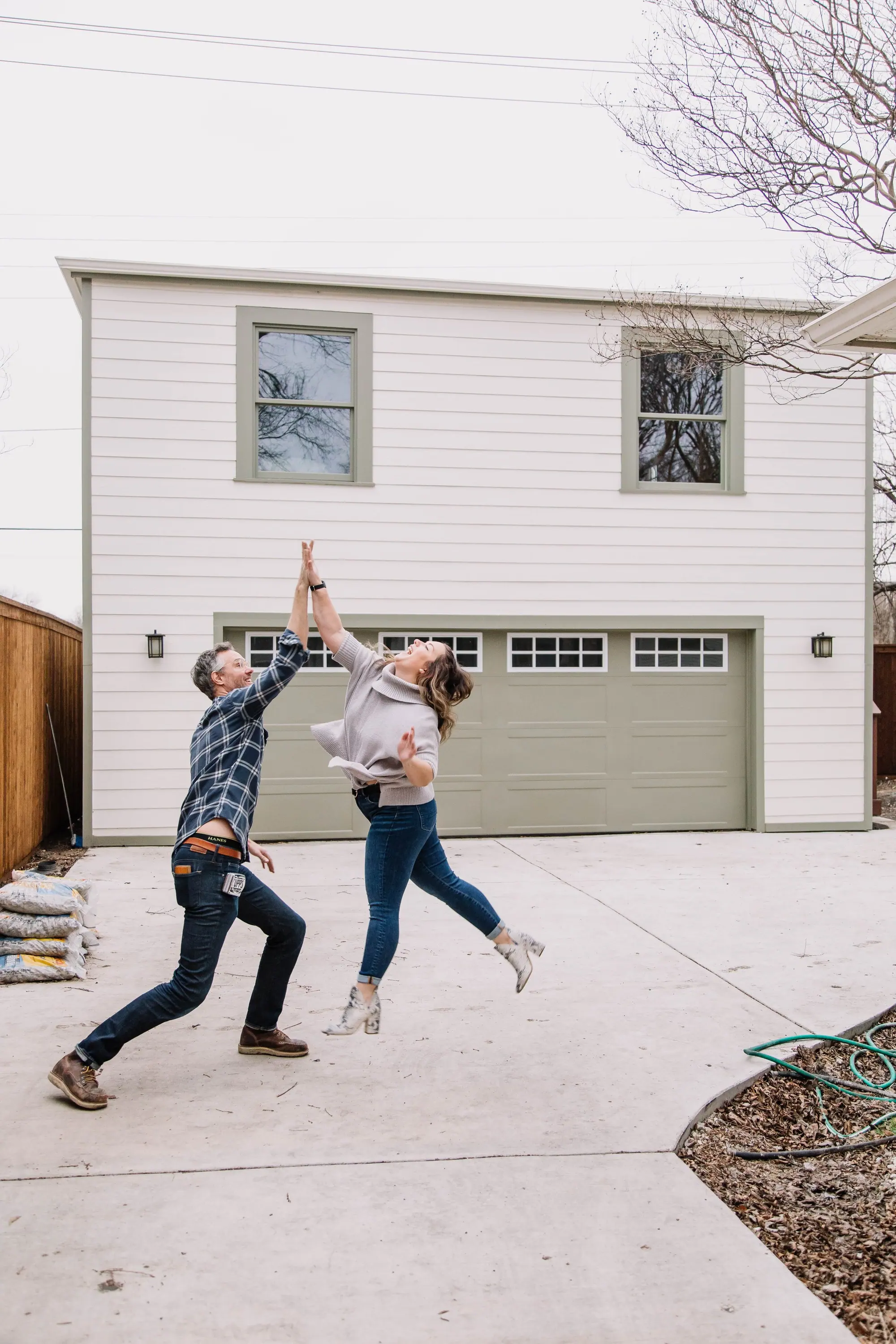 A Fort Worth couple leaping into a mid-air high-five in front of their just-finished 6th Ave Homes project