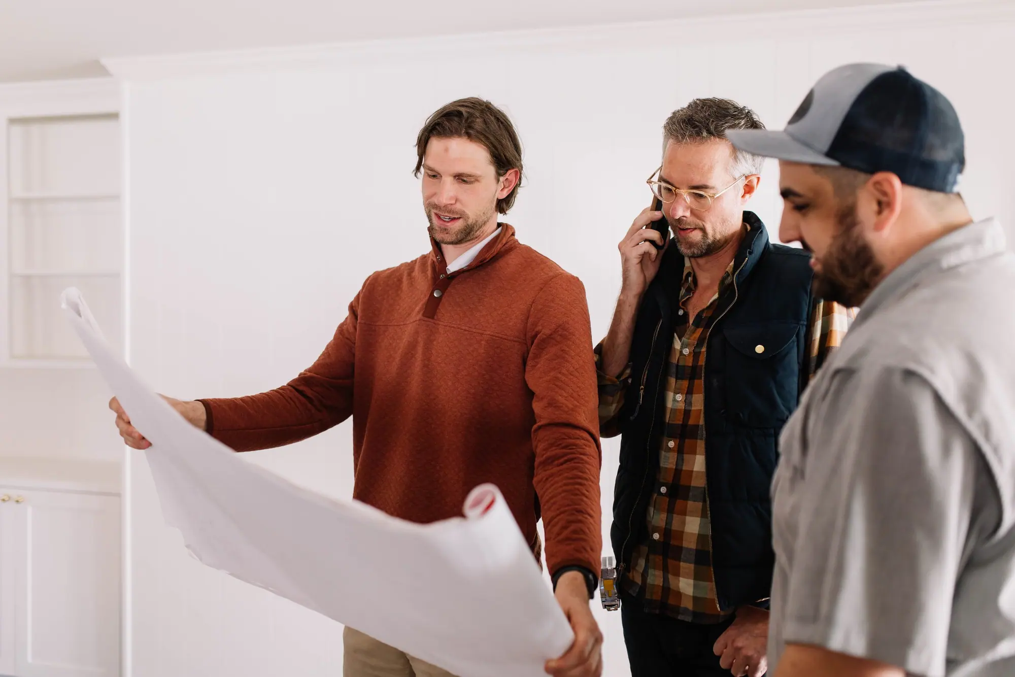The build team huddled over an unrolled plan inside an unfinished Fort Worth home