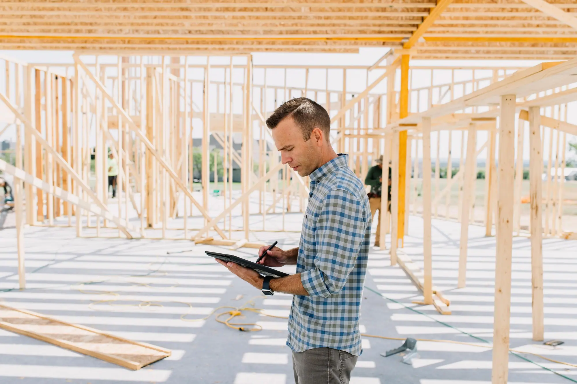 A builder reviews plans on the framing deck of a 6th Ave Homes new build in Fort Worth