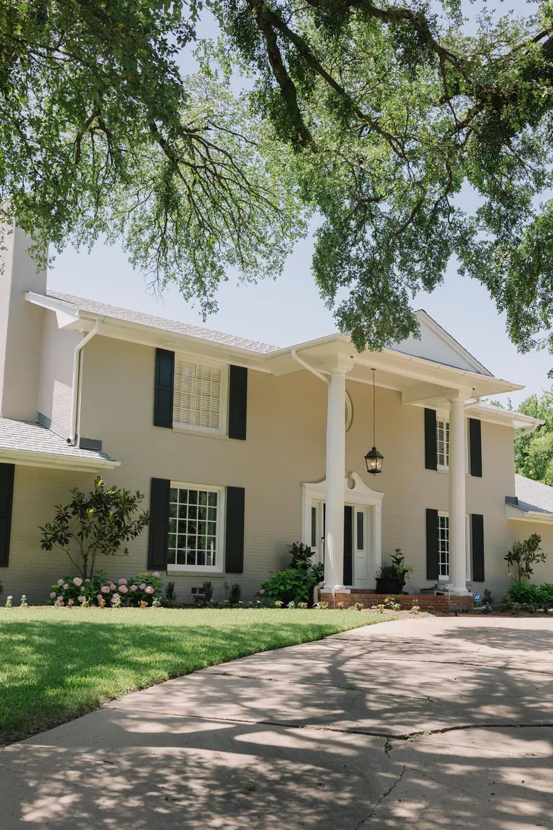 A stately custom home with a two-story columned portico under mature oaks in Fort Worth