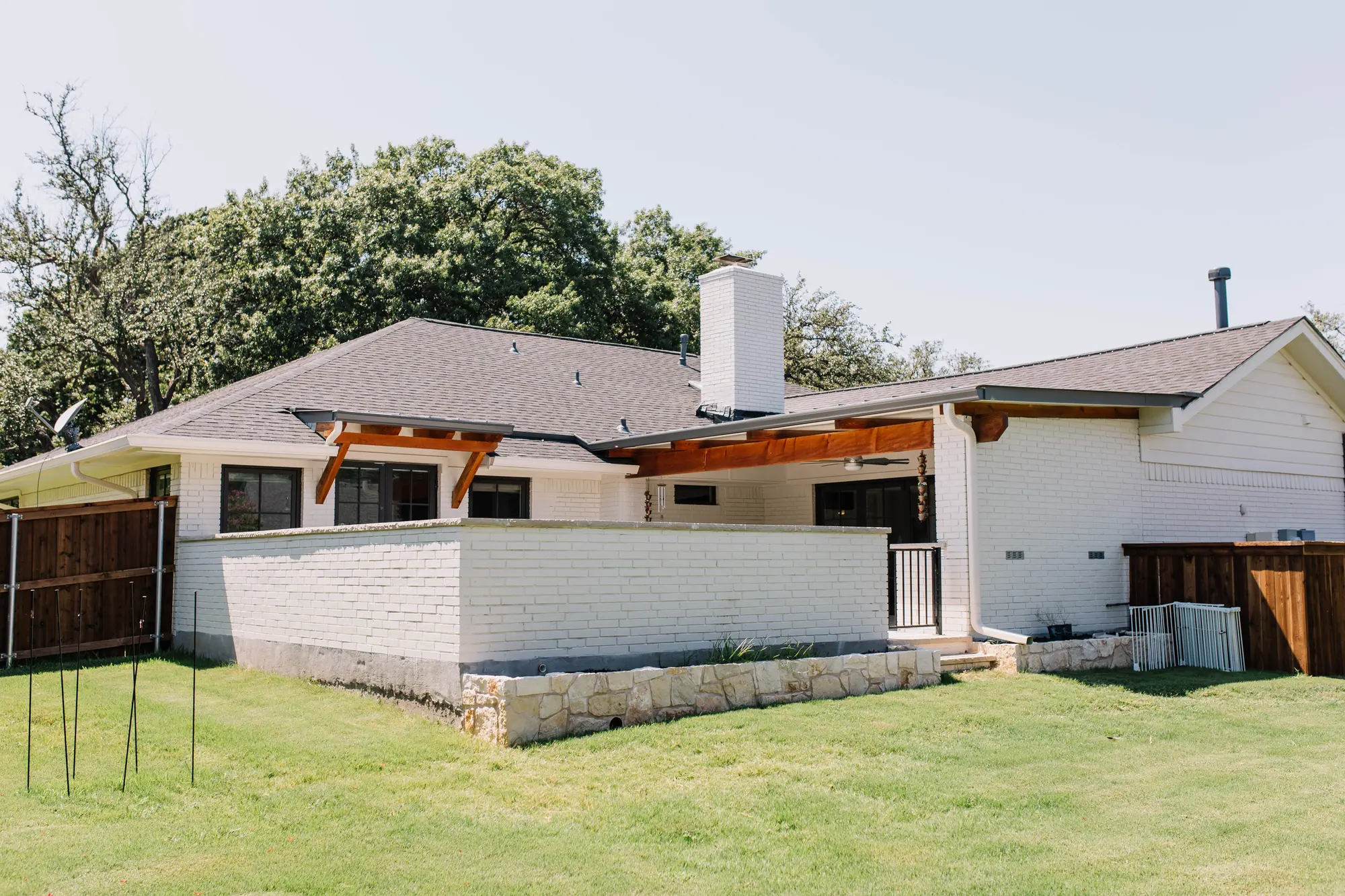 The back of a Wedgwood house from the lawn, with two cedar covers sharing the roofline of the white-brick house