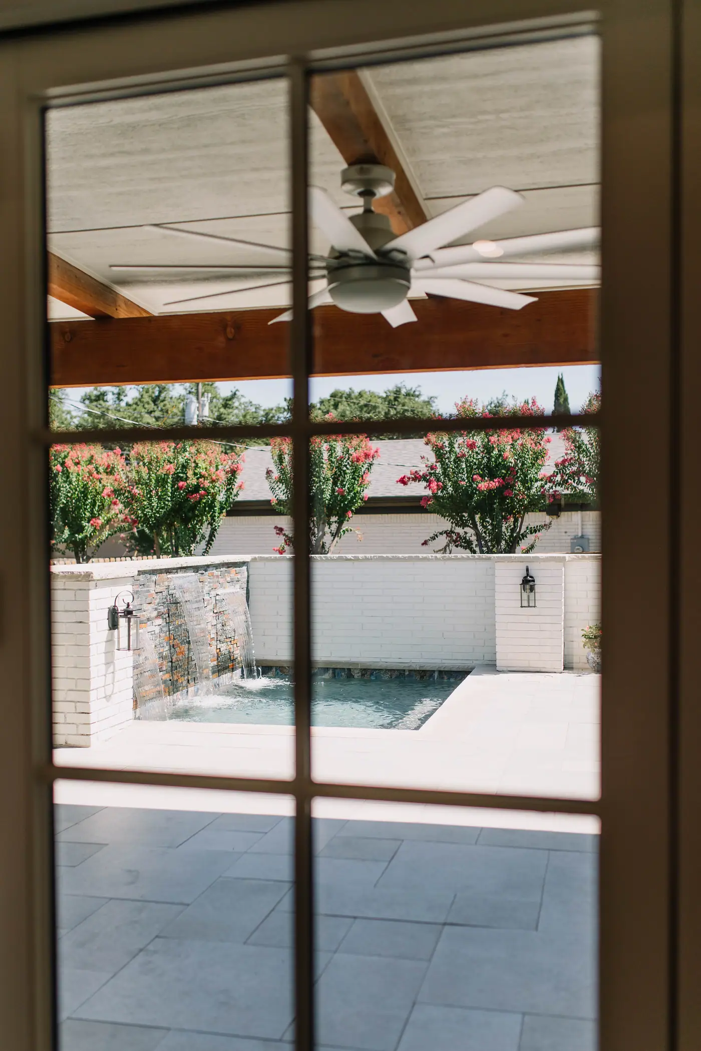Looking out through a French door onto a cedar-beamed patio cover with a ceiling fan, and a plunge pool beyond it