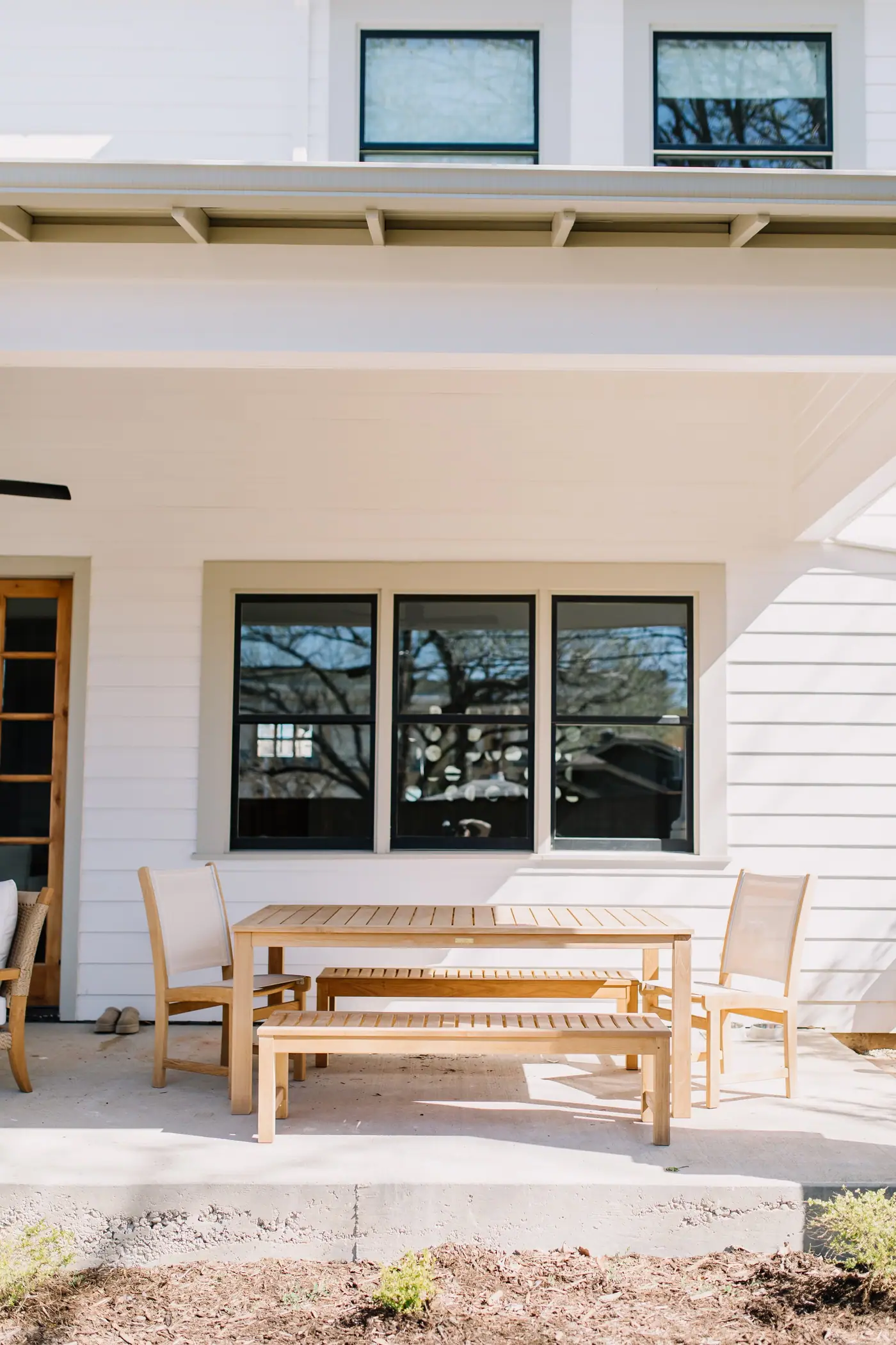 Covered porch with a long dining table at a Fort Worth custom home by 6th Ave Homes