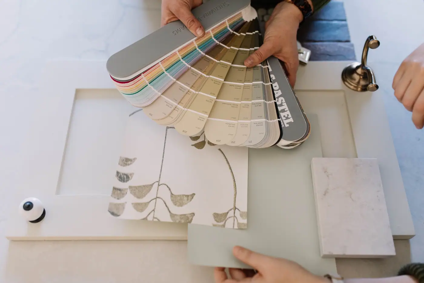 Hands holding fabric and finish swatches over a table of material samples