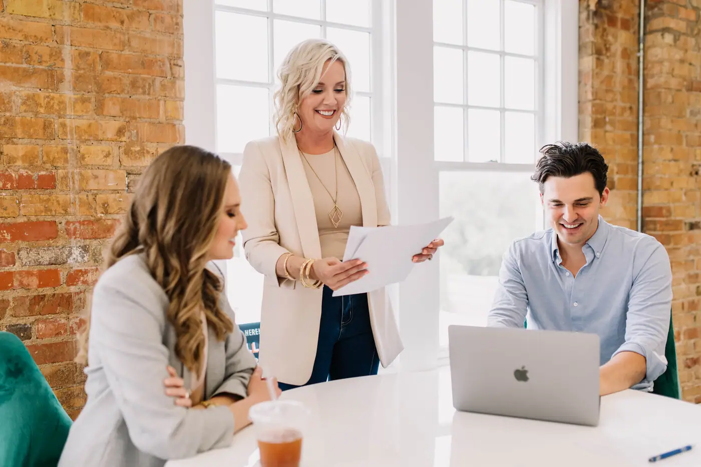 Three 6th Ave Homes agents talking over a laptop at the office table