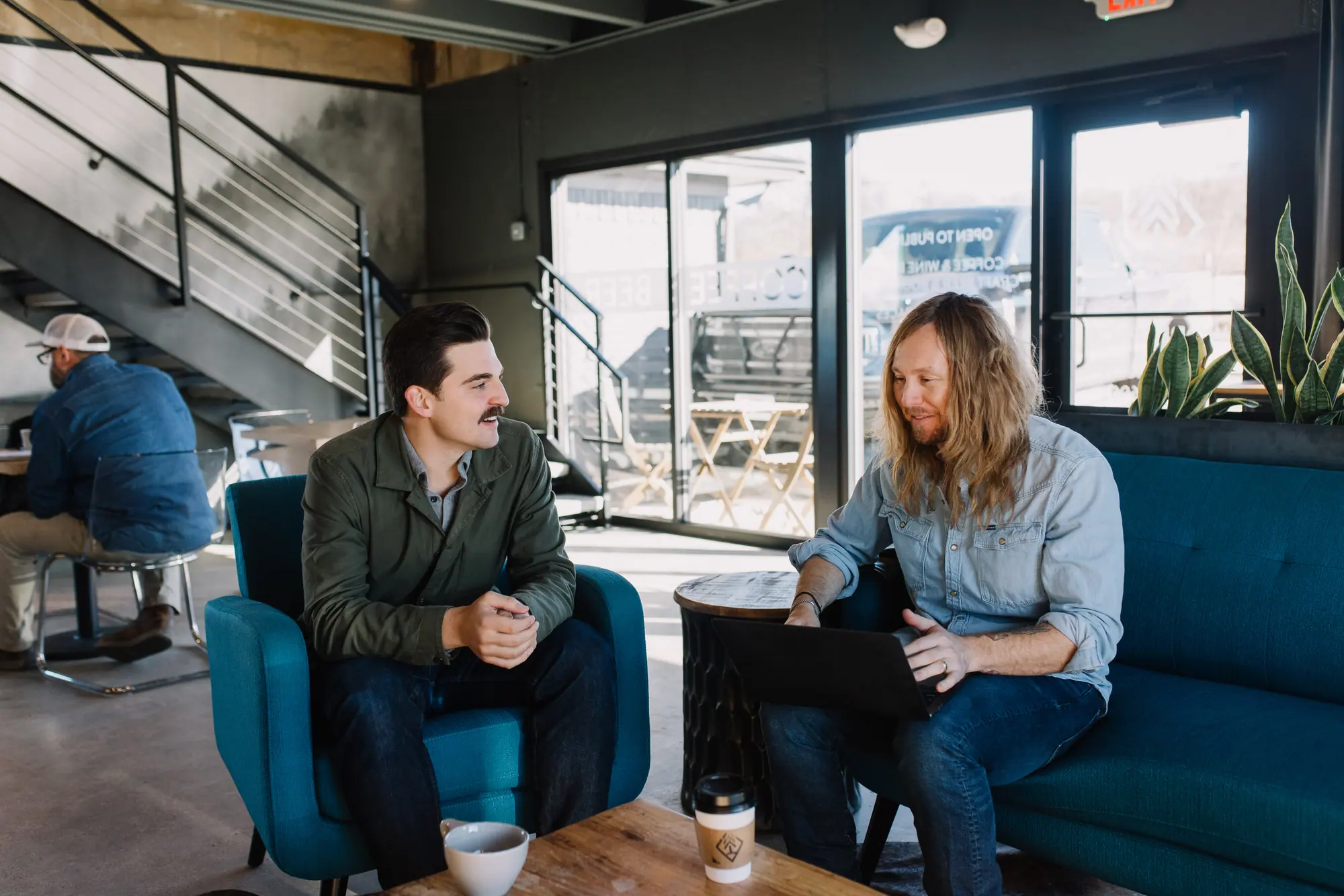 Two people talking over coffee and a laptop in a café