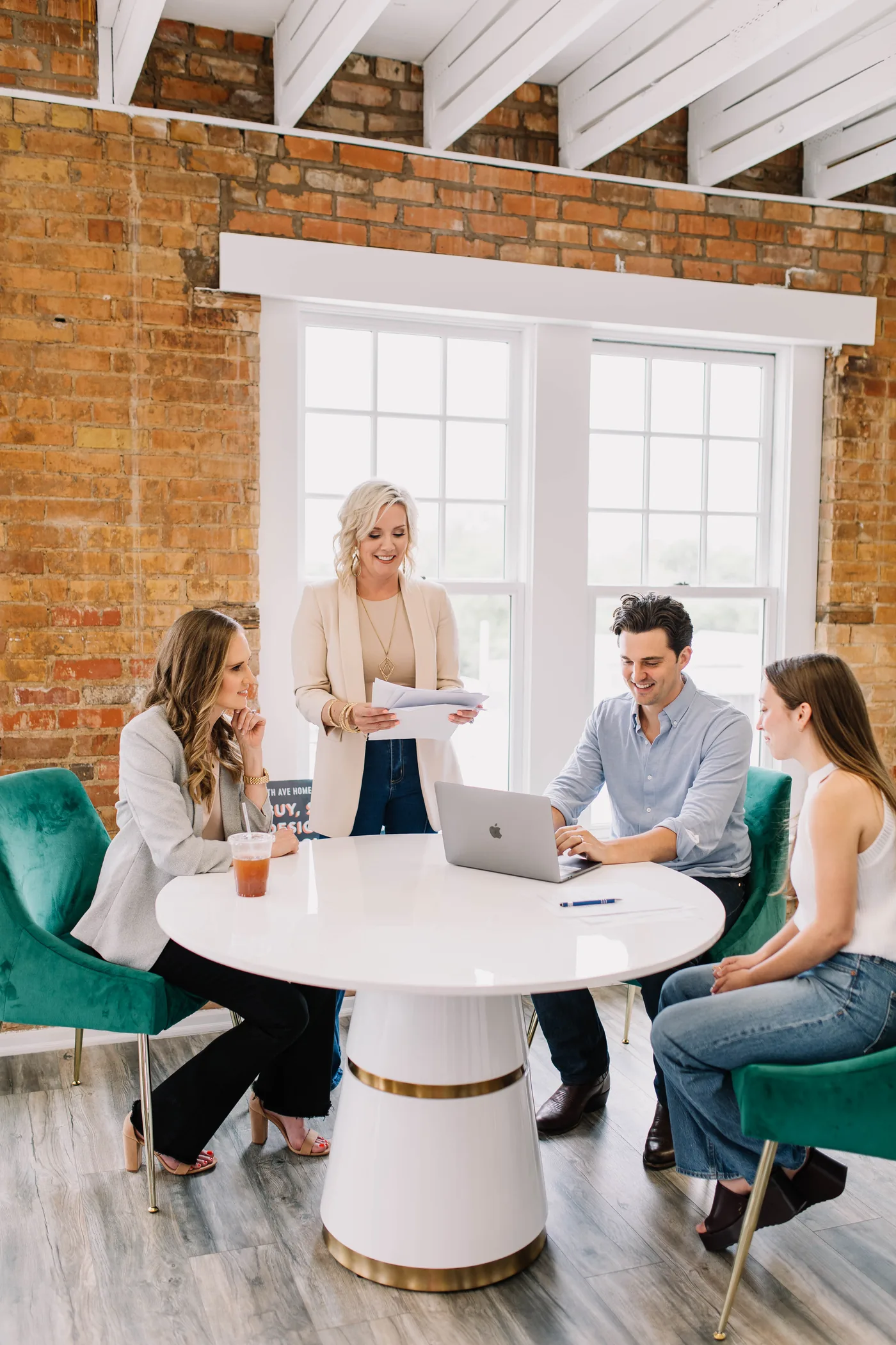 A 6th Ave Homes agent leading a training session for three agents around the office table