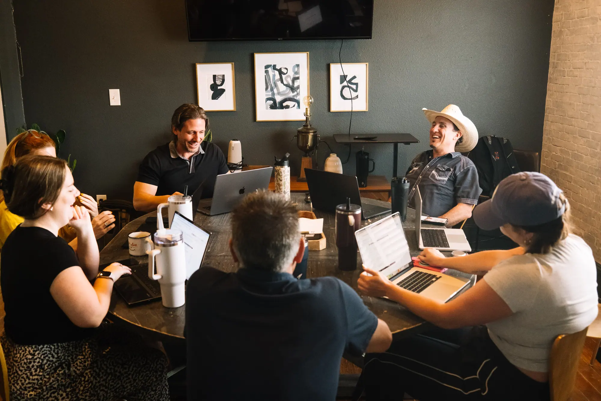 The 6th Ave Homes support team laughing around the table at their weekly meeting