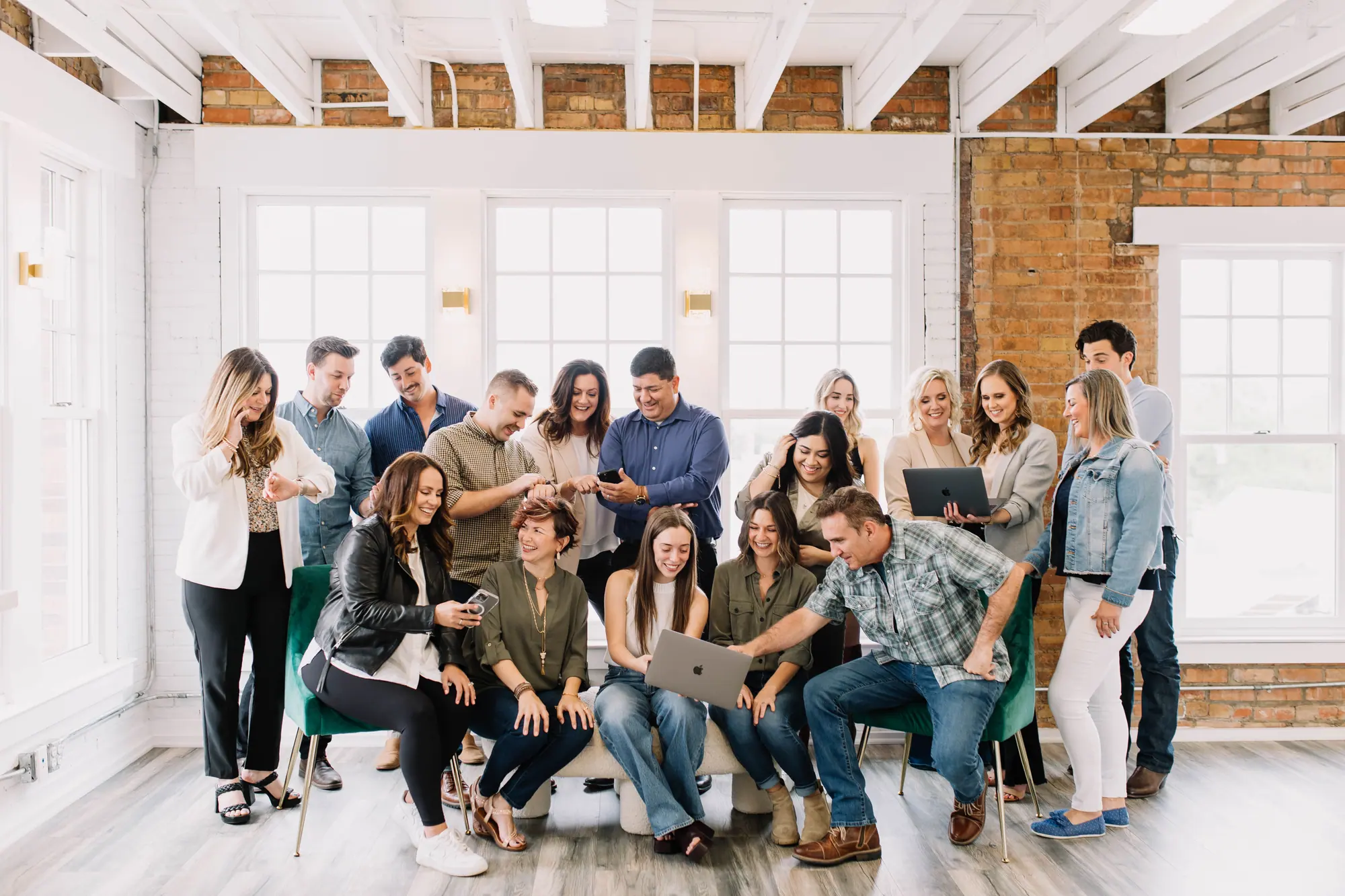 The 6th Ave Homes agent team crowded around a laptop together, laughing