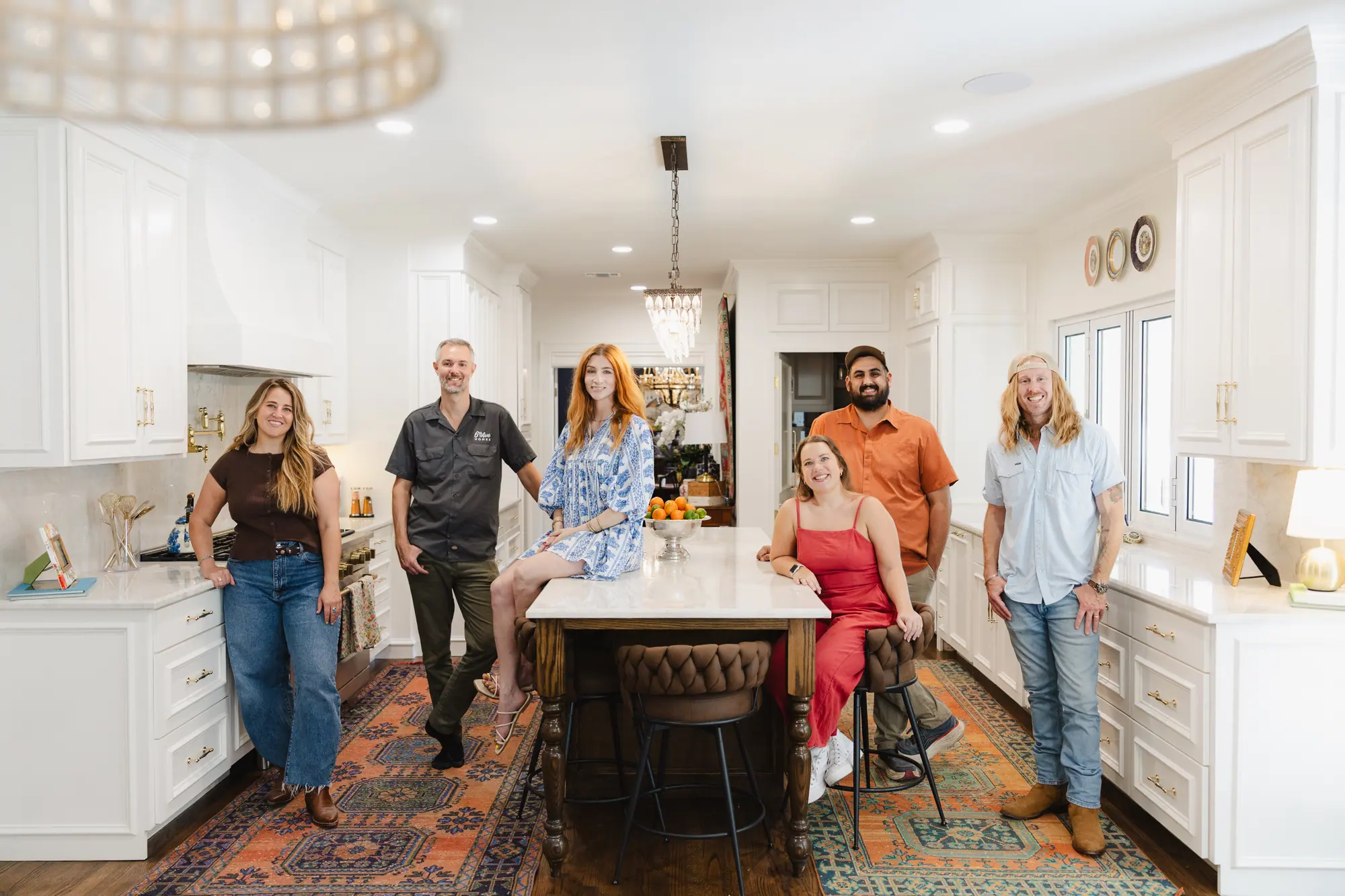Our team smiling together in a finished white kitchen with an island and two patterned rugs.