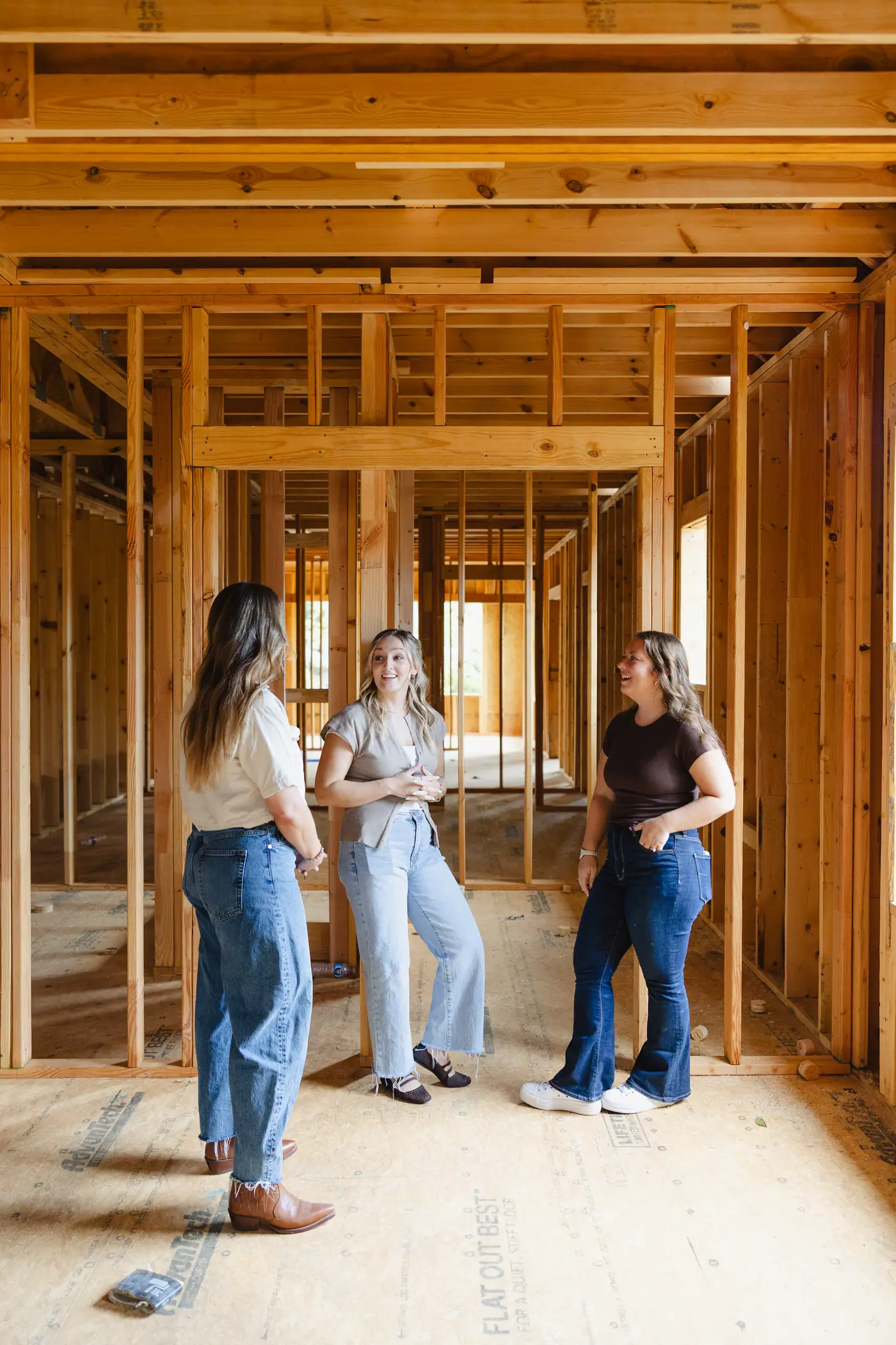 Three 6th Ave Homes team members talking in the framed hallway of a house under construction