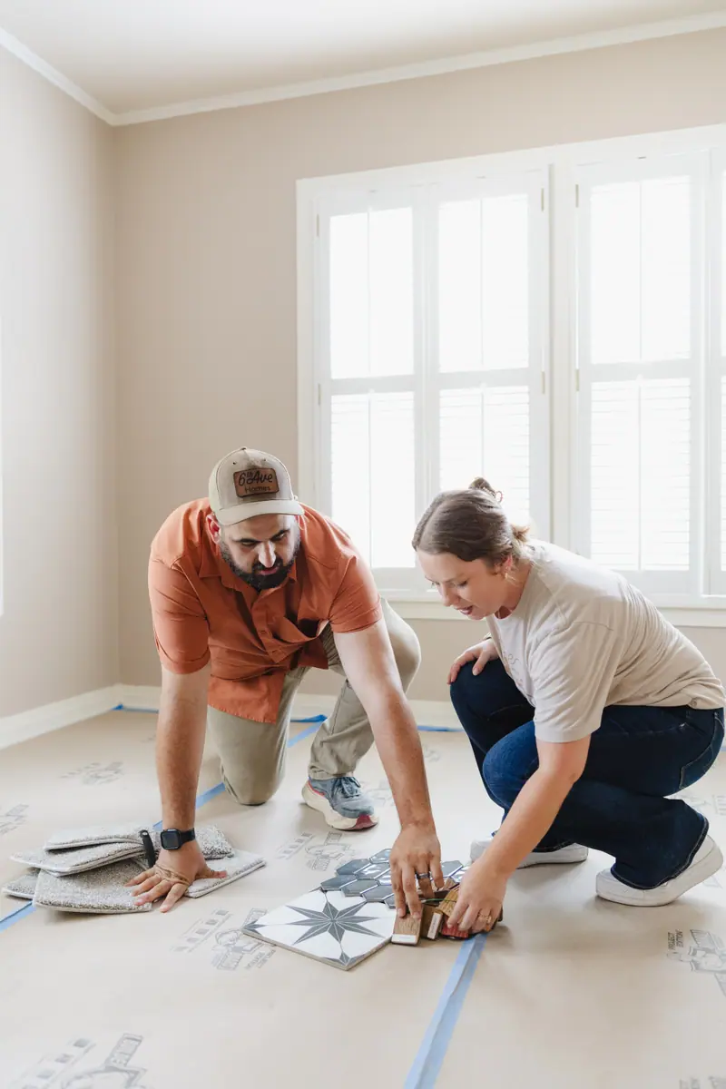 Two of our team, down on a papered floor, set tile, carpet and wood samples side by side.