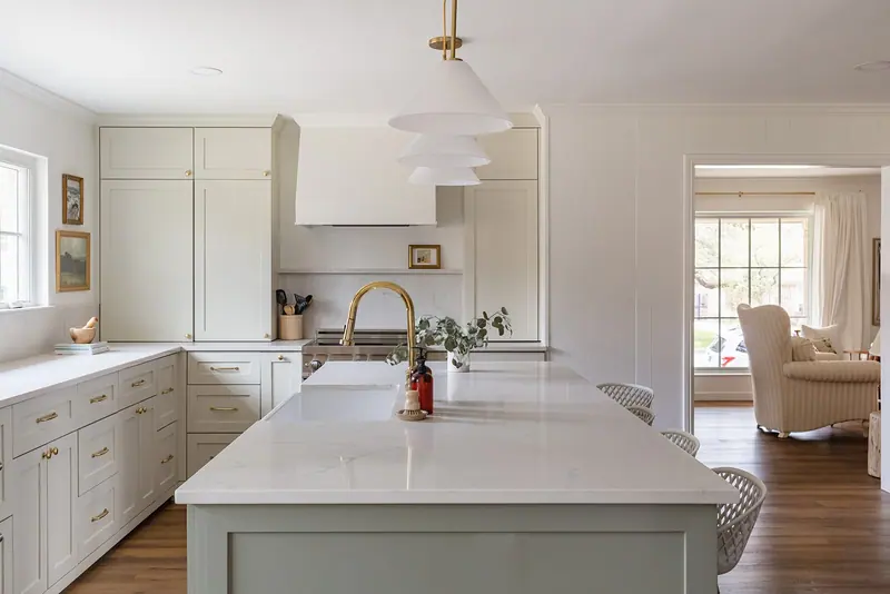 A greige marble island with a brass faucet opening to the living room in a Ridglea Country Club kitchen