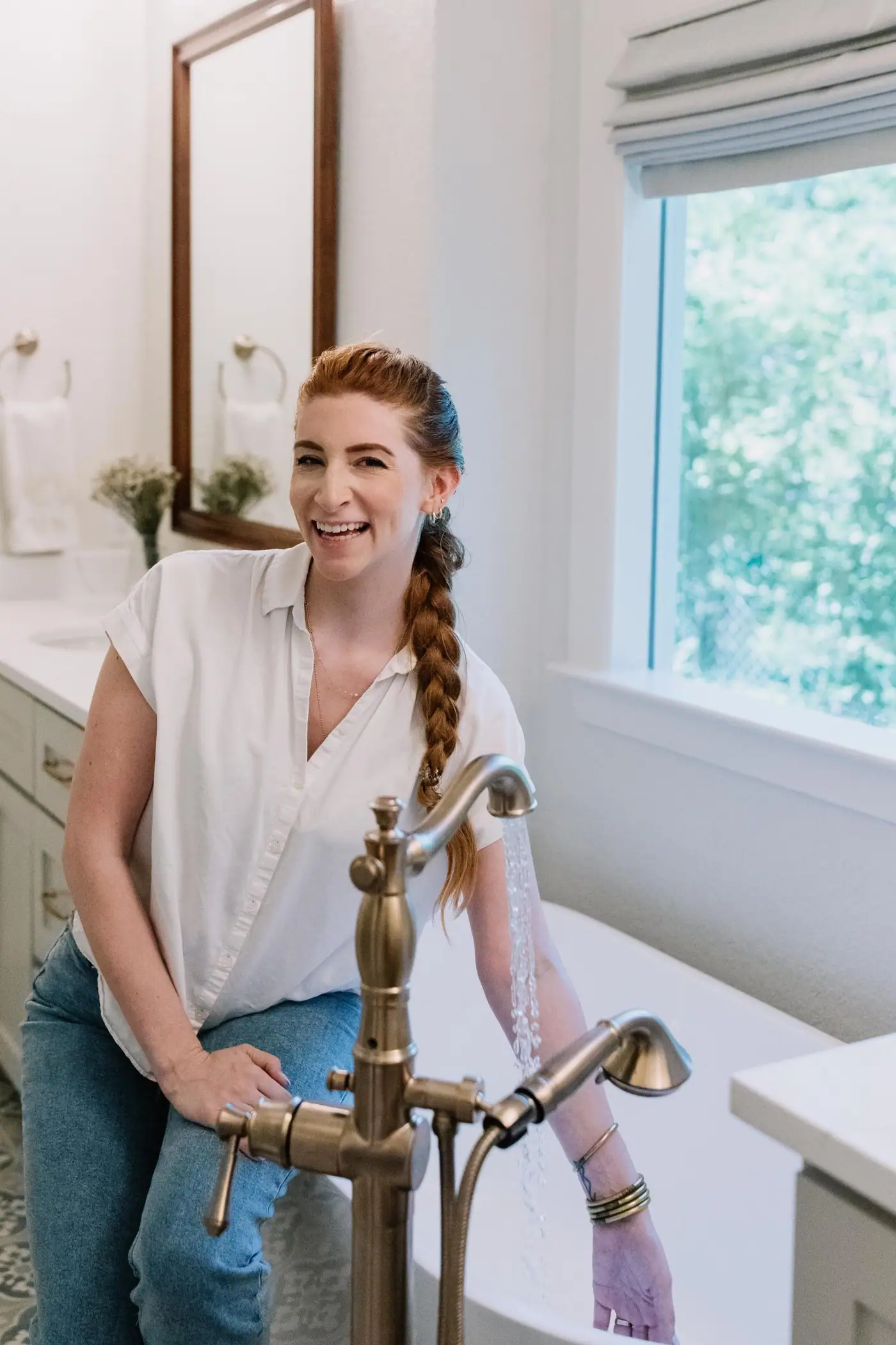 A 6th Ave Homes construction director laughing beside a freestanding tub as the filler runs in a finished Fort Worth master bath