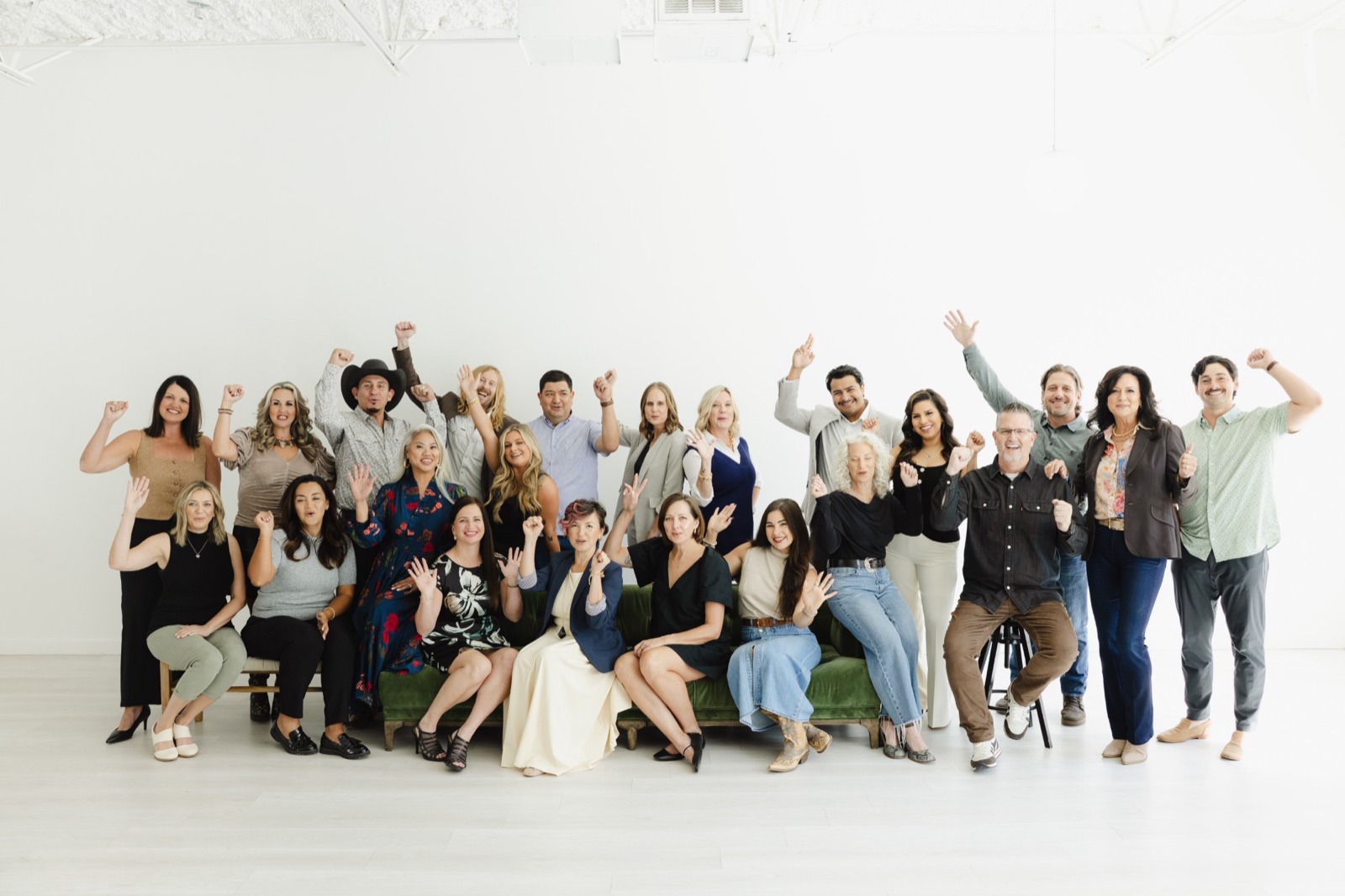 The whole 6th Ave Homes team cheering together around a green velvet couch at the 2025 team shoot