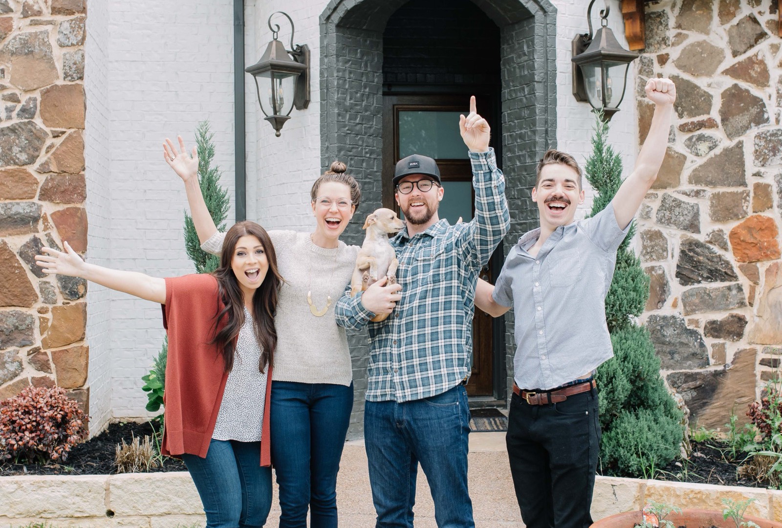 Four Fort Worth buyers cheering, one holding their new puppy, on the front walk of the grand white-brick home they just closed on with 6th Ave Homes