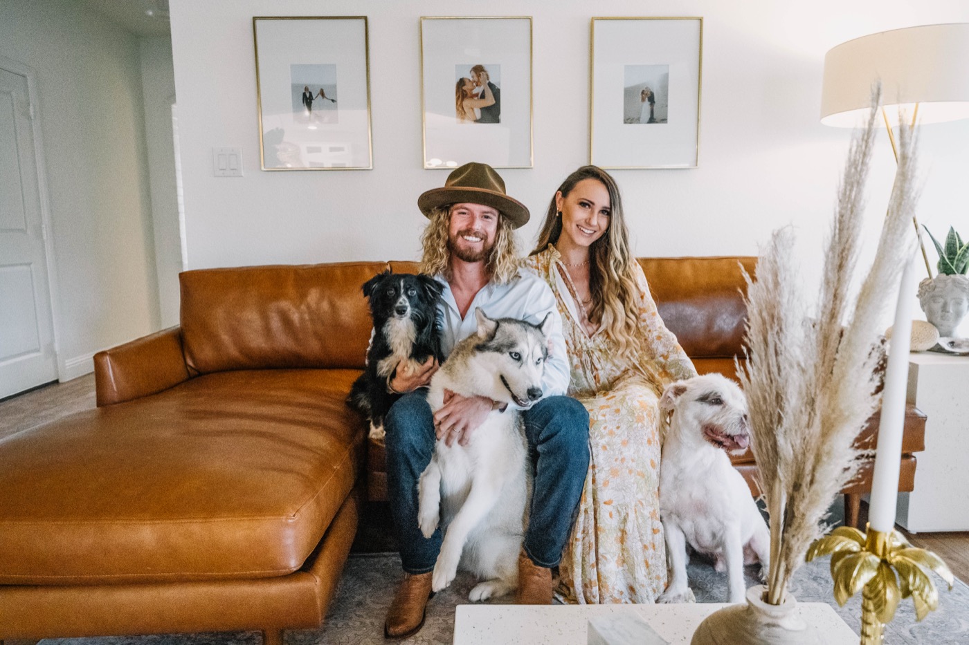 A couple at home on their leather couch with their three dogs, settled into the house 6th Ave Homes helped them buy