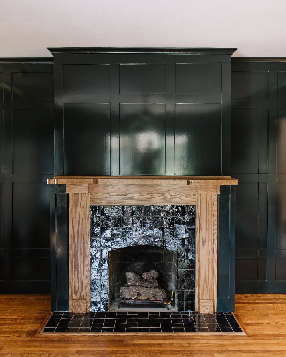 Green-paneled fireplace with a wood mantel and dark tile surround in a Near Southside Fort Worth renovation