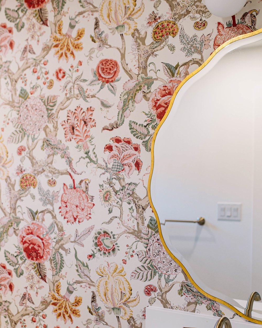Powder room with maximalist floral wallpaper, a scalloped mirror, and brass fixtures in a Fort Worth remodel