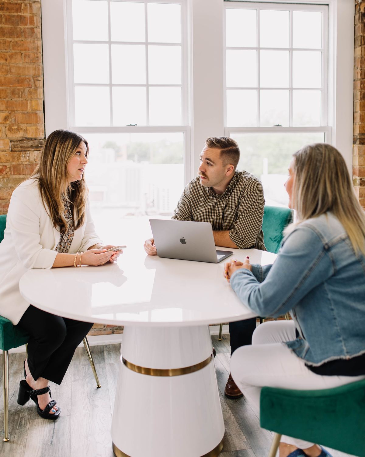 Three 6th Ave Homes team members in a meetup around the table in their brick-walled Fort Worth office