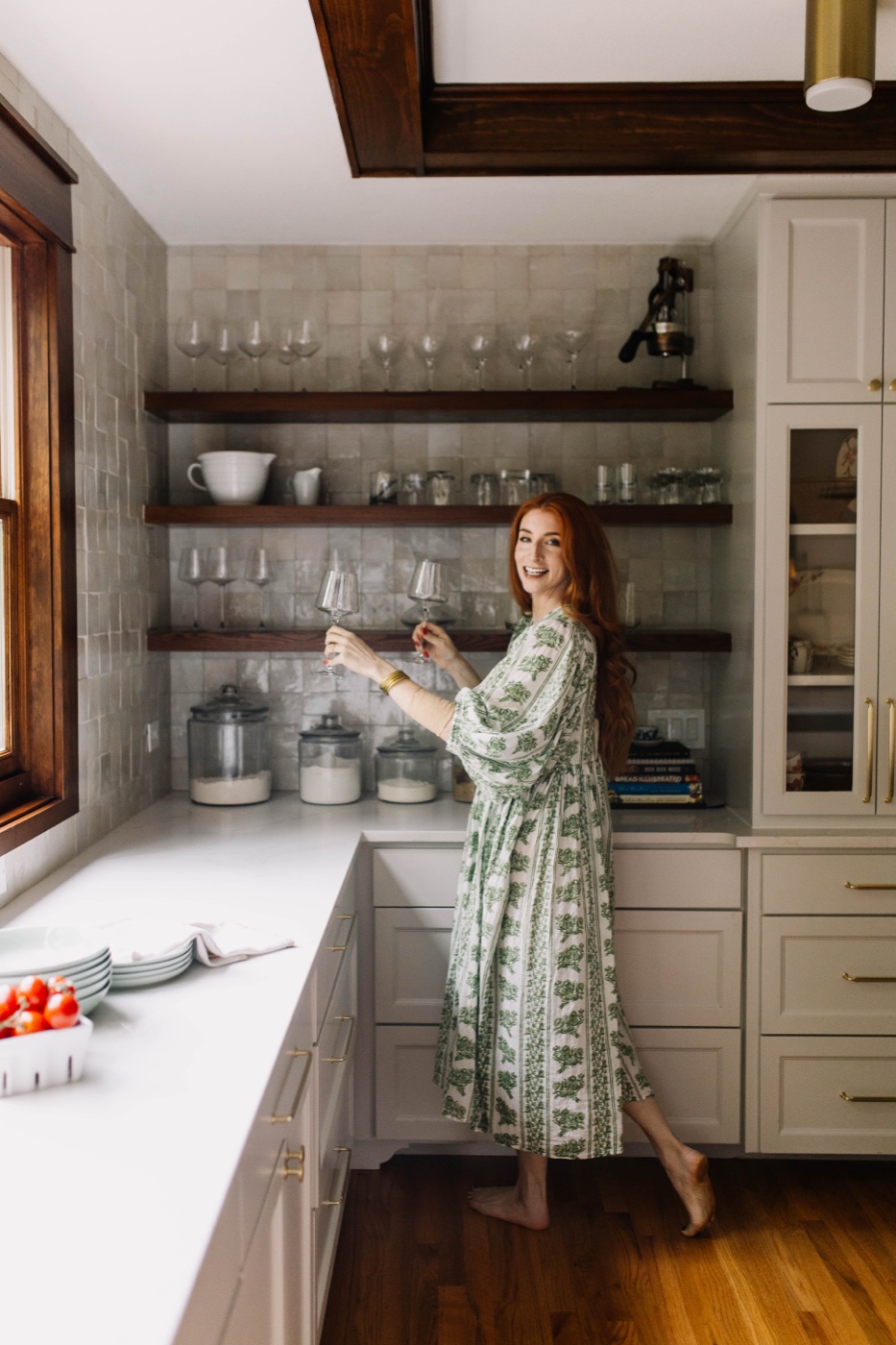 A woman raising a glass in the light-filled, custom-designed kitchen 6th Ave Homes created for her Fort Worth home