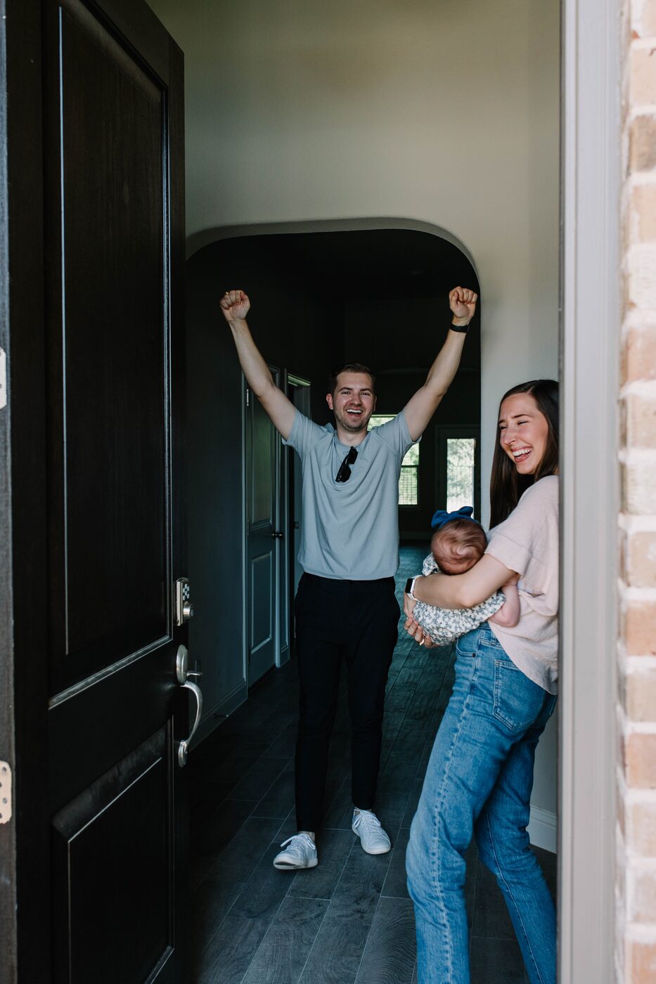 A young Fort Worth family walking into the home they just bought, arms up