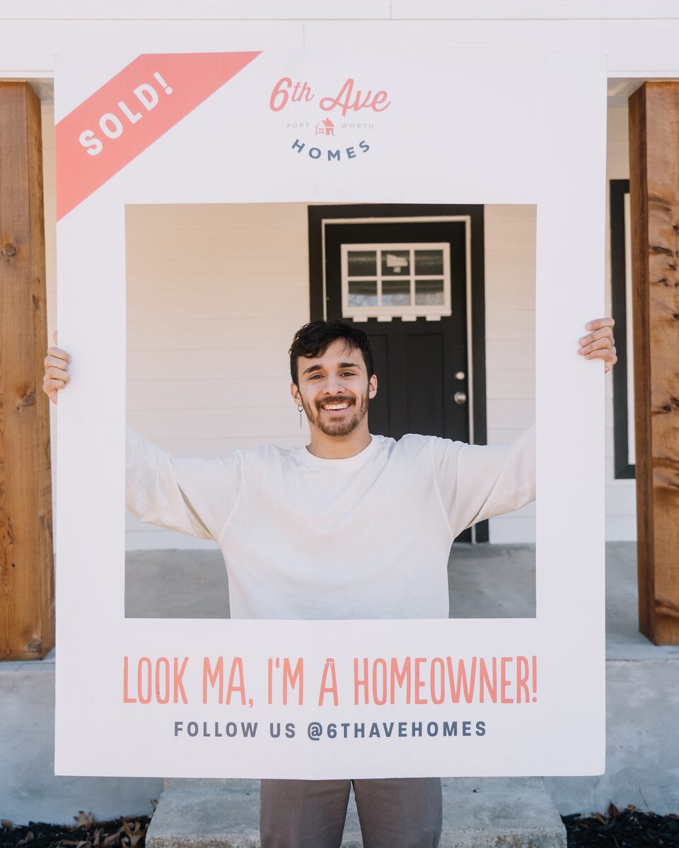 A new Fort Worth homeowner celebrating behind a 6th Ave Homes ‘Sold’ sign