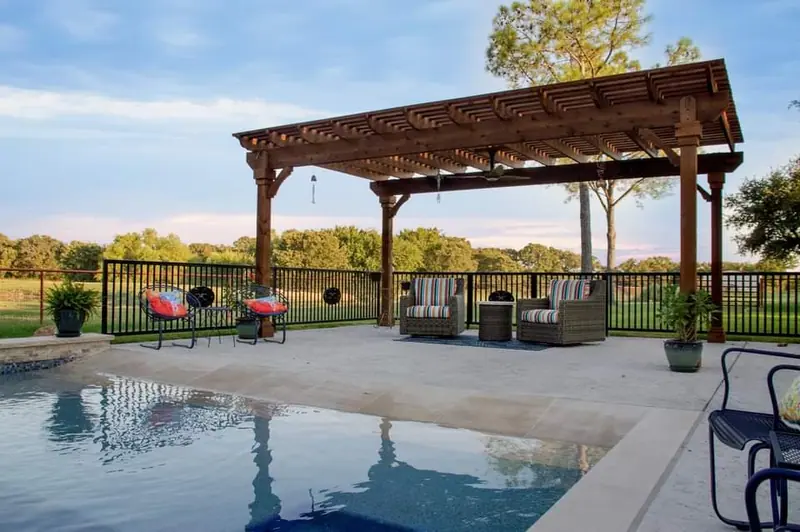 A cedar pergola shading an outdoor lounge beside the pool