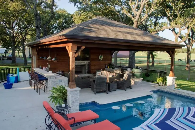 A cedar pool cabana with a bar, fireplace, and swim-up stools at the pool edge