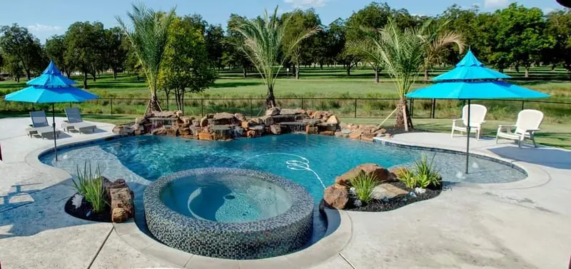 A free-form pool with a pebble spa and rock waterfall