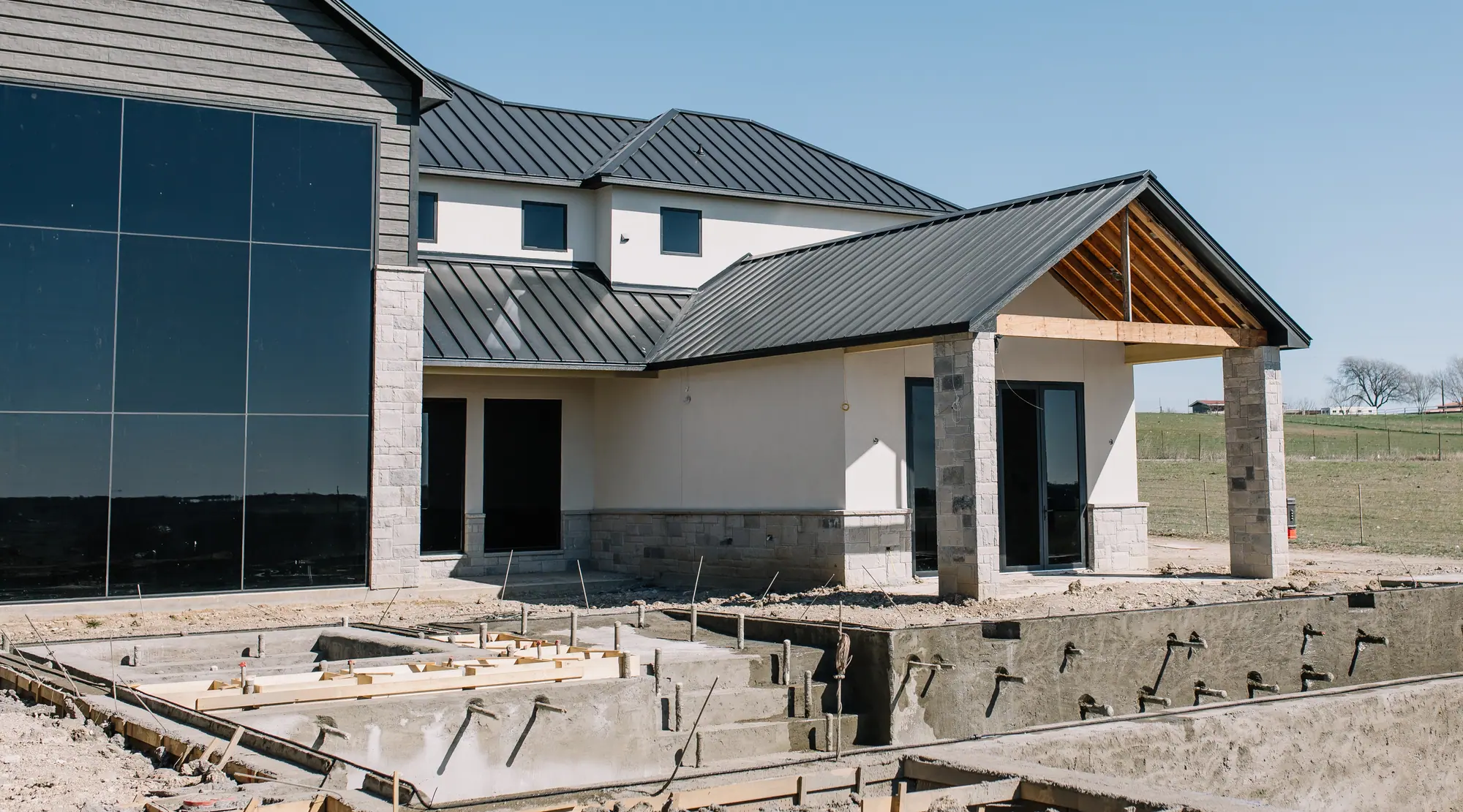 A gunite pool shell and spa with their steps and plumbing stubs, shot and curing right against a house’s new covered patio