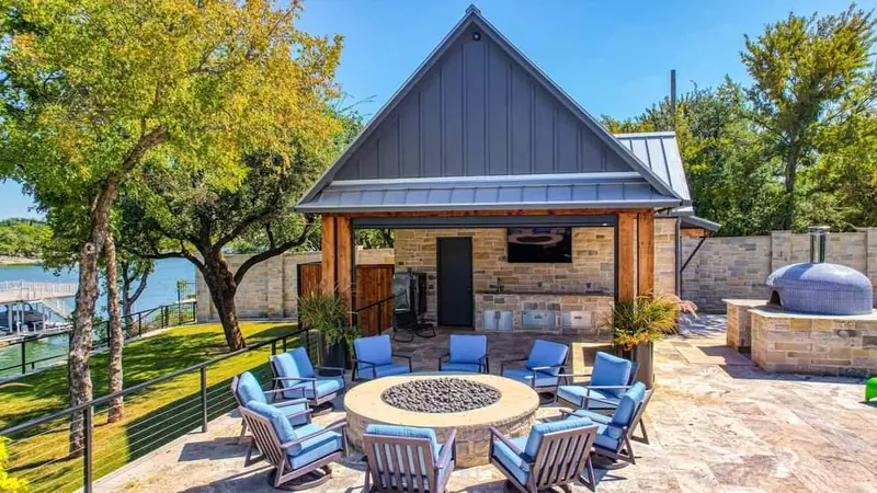 One backyard with every element planned together: pool house, outdoor kitchen, pizza oven, and a fire pit lounge by the water