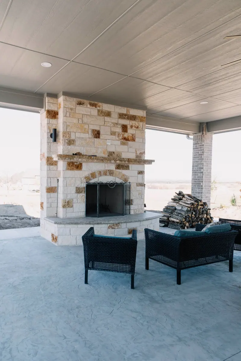 A raw covered patio with a firewood pile and dirt yard