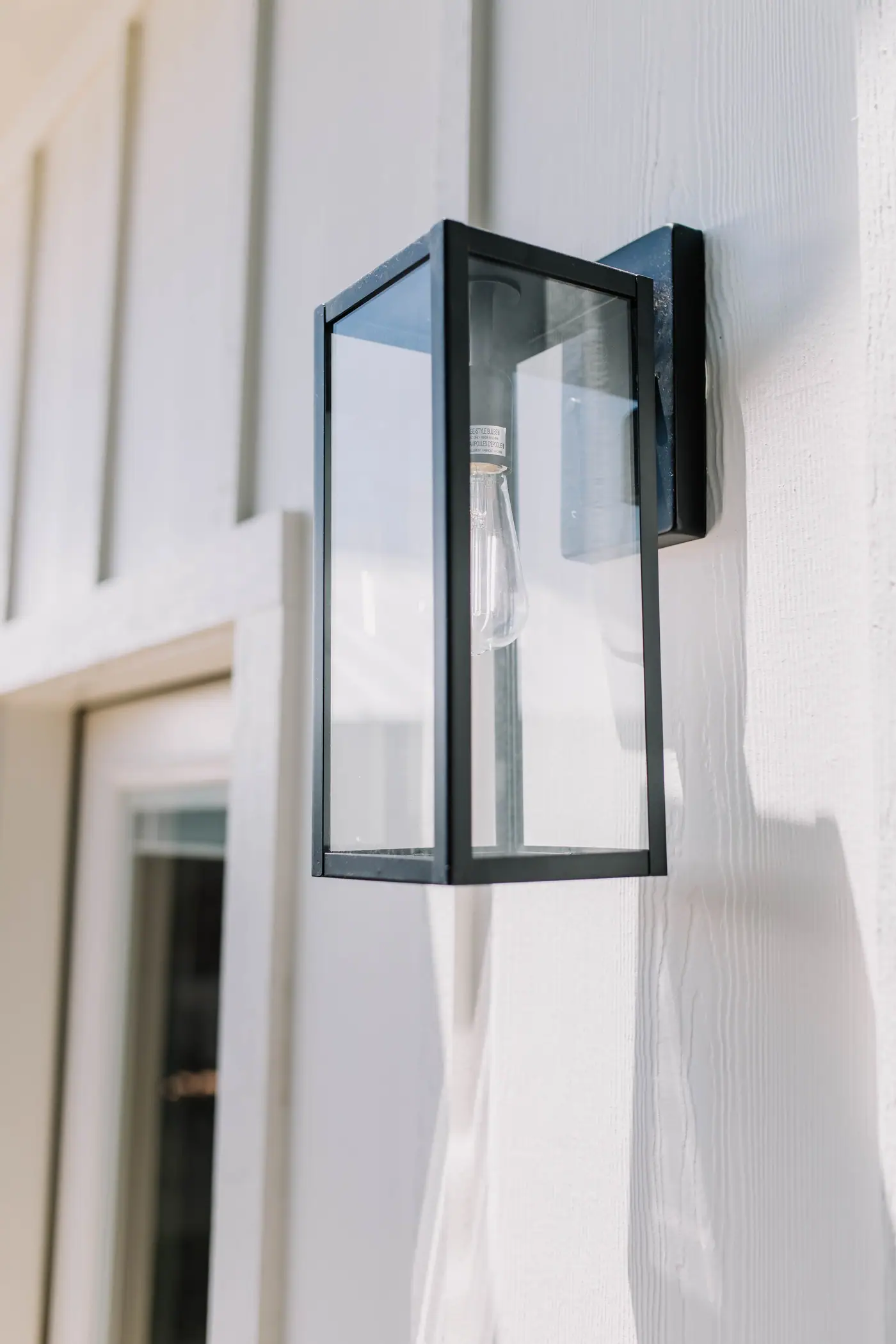Black-framed glass lantern on the white board-and-batten siding of an Arlington Heights backyard casita by 6th Ave Homes