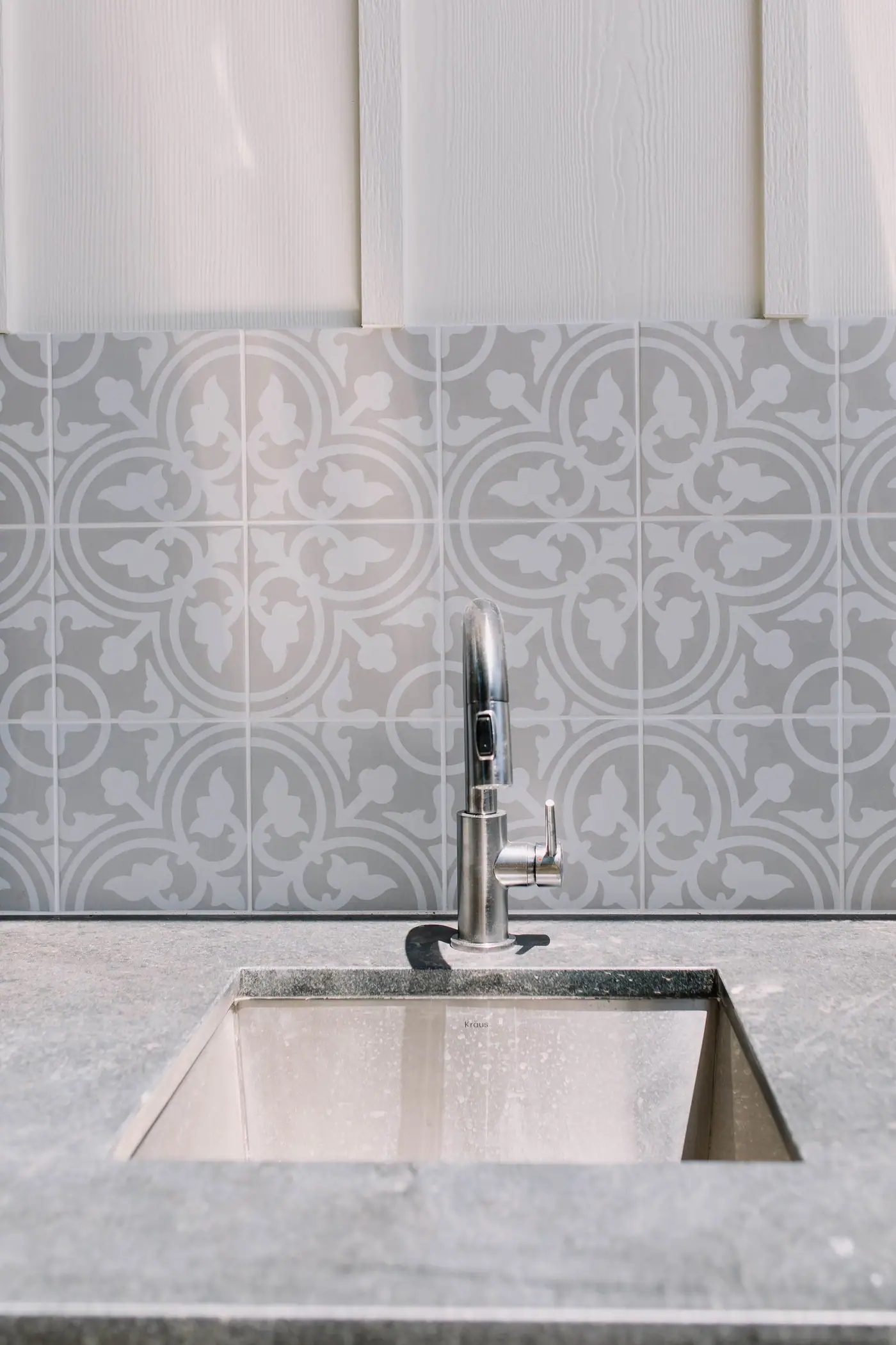 Stainless undermount sink in a honed gray counter against patterned gray cement tile at an Arlington Heights backyard casita by 6th Ave Homes