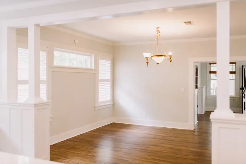 A dining room with a brass chandelier and craftsman columns