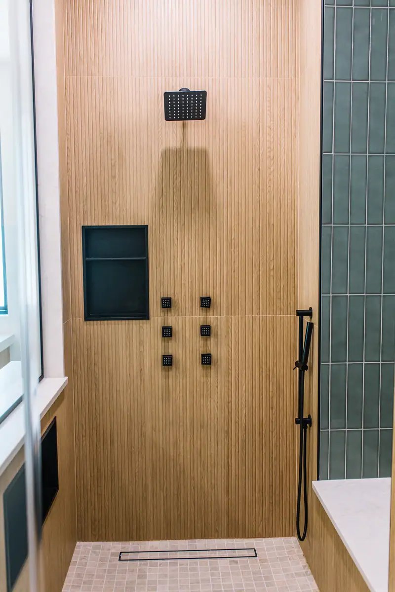 Large zero-entry shower with multiple shower features, oak-look ceramic tile and sage ceramic tile