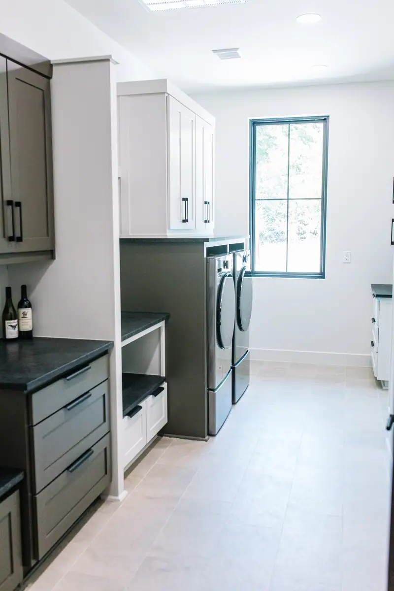 Laundry room with dark cabinetry, a folding counter and a window above the machines