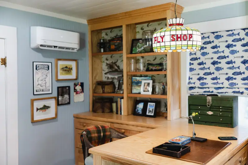 Custom built-in cabinetry and thrifted vintage art around the fly-tying peninsula, under the stained-glass Fly Shop chandelier