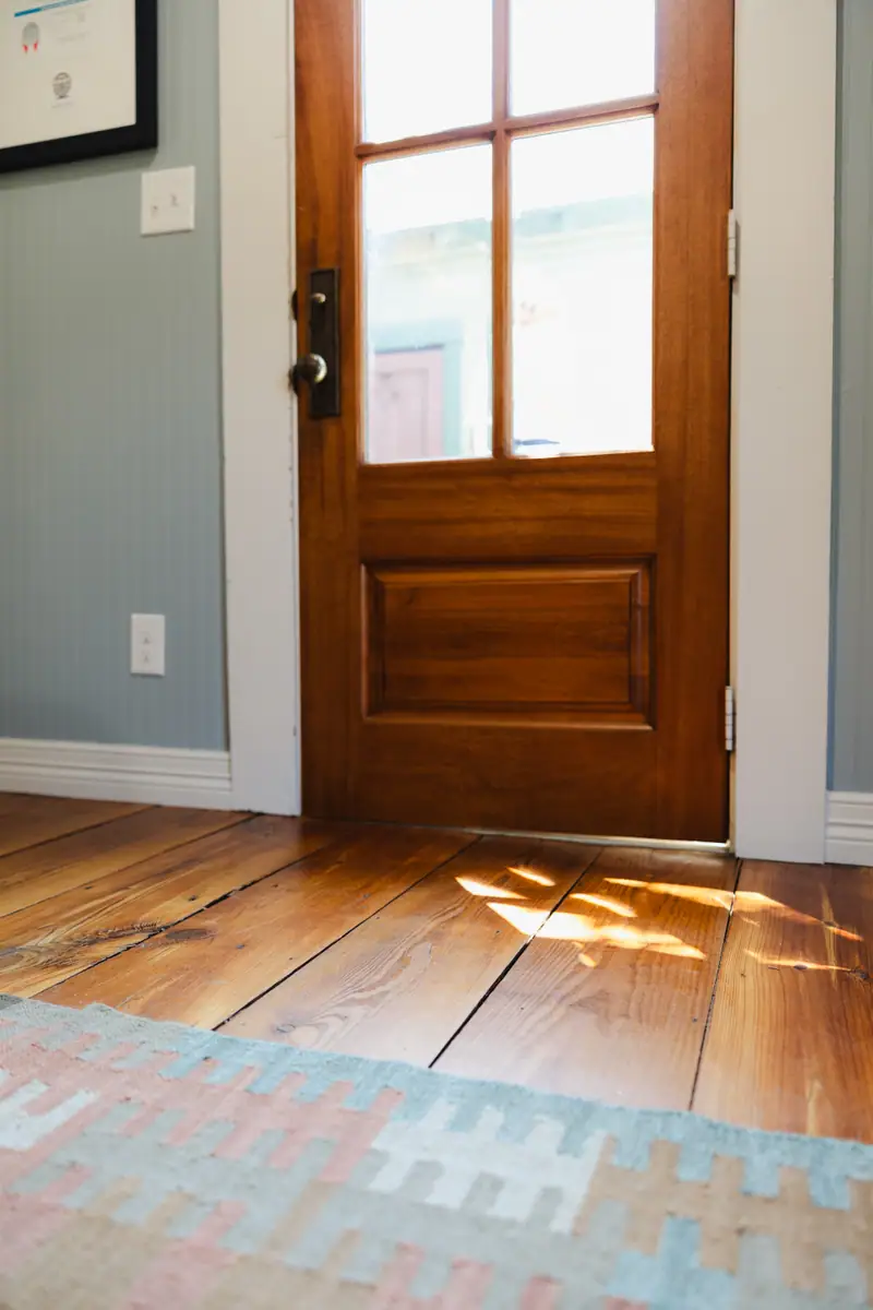 Wood entry door opening onto the reclaimed wood flooring and a vintage rug