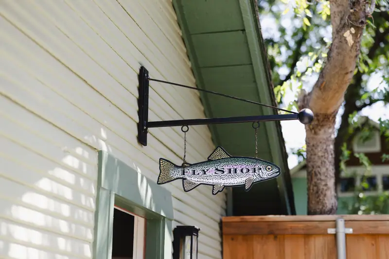 Fish-shaped Fly Shop sign hanging from the eave of the restored structure