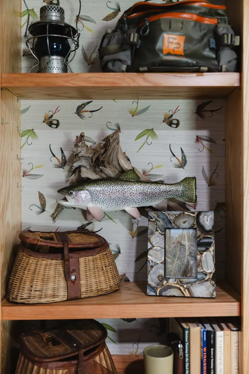Built-in shelf holding a mounted fish, tied flies and vintage creel baskets