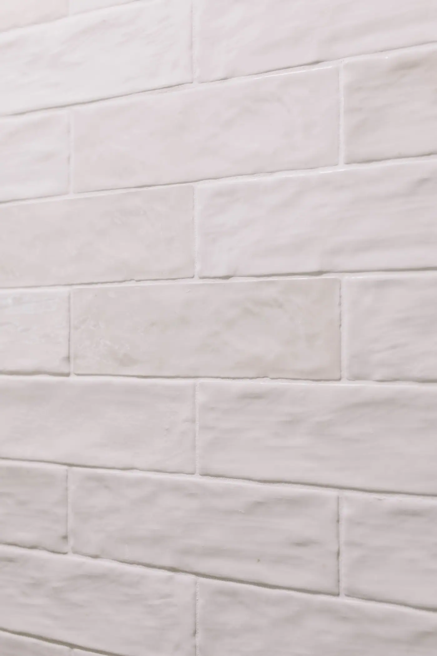 A wall of handmade-look white subway tile, the glaze varying from tile to tile.