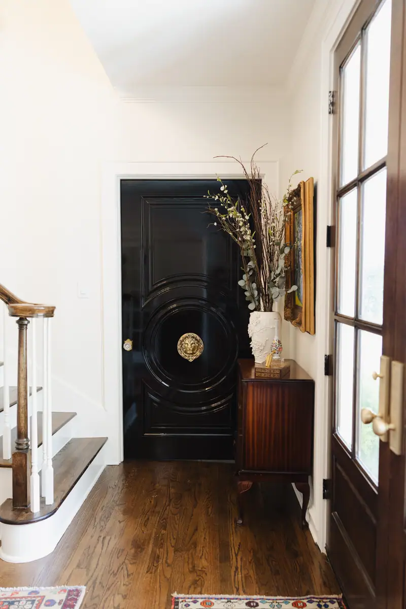 Entry with a black lacquered front door, brass lion-head knocker, red oak floors and the curved base of the staircase