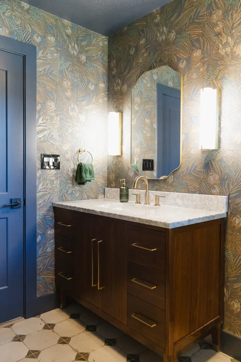 Half bath wrapped in moody blue and gold botanical wallpaper, with a dark wood vanity and a checkerboard tile floor