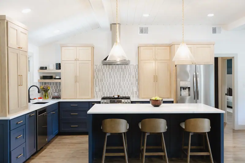 Open kitchen in a Westcliff home in Fort Worth with a navy island, light wood cabinetry, picket tile backsplash and a vaulted shiplap ceiling