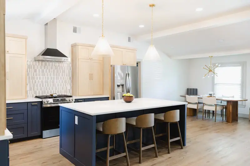 Kitchen island with wood bar stools and pendant lights, looking through to the dining room of the Westcliff refresh