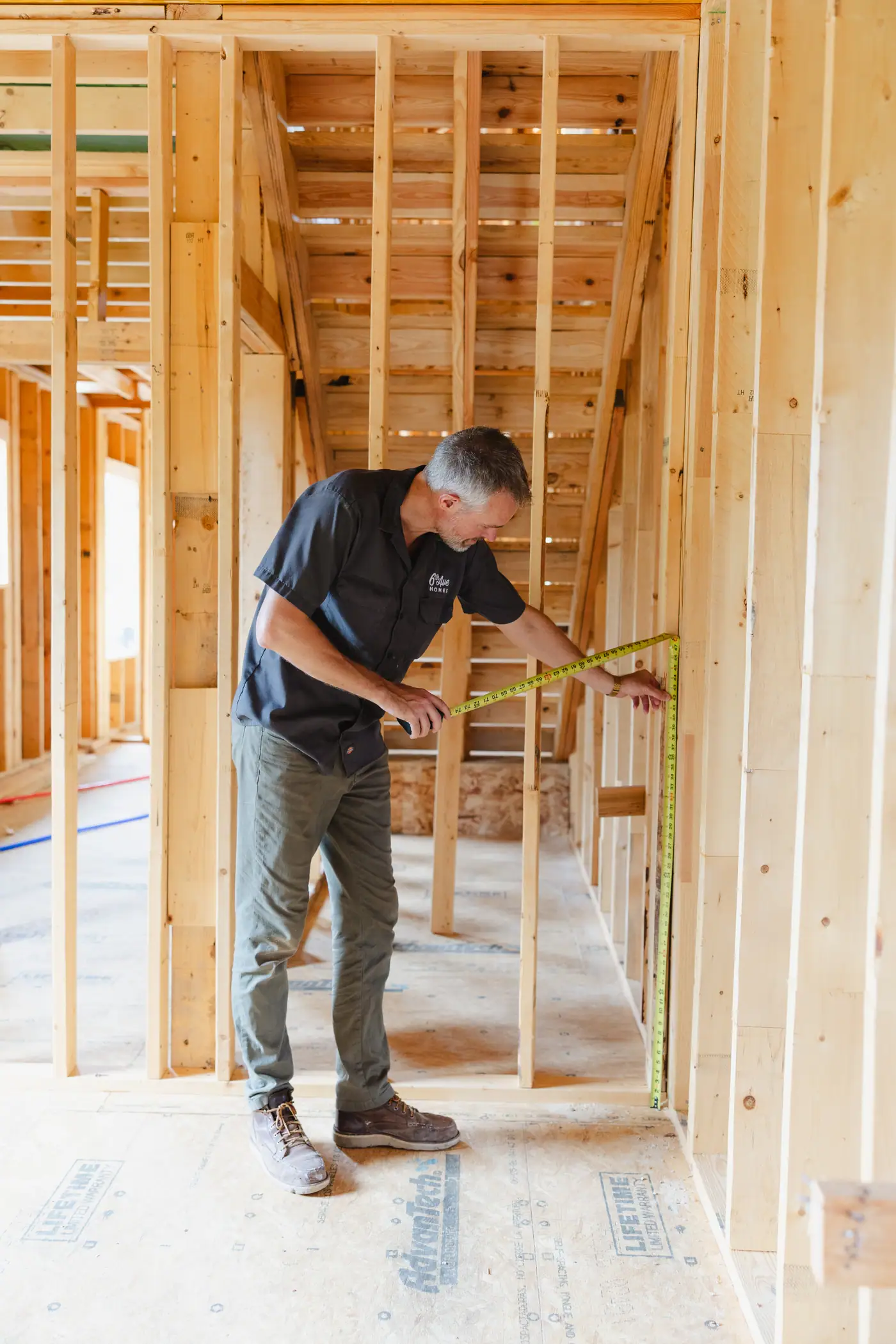 A 6th Ave Homes team member measuring inside new stud framing during a Fort Worth renovation