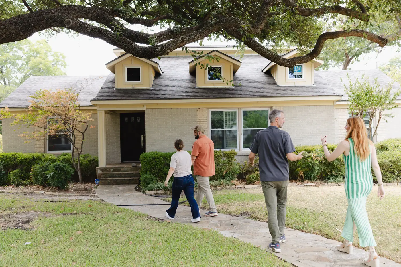 Four 6th Ave Homes team members walking up to a Fort Worth ranch house for a first walk-through
